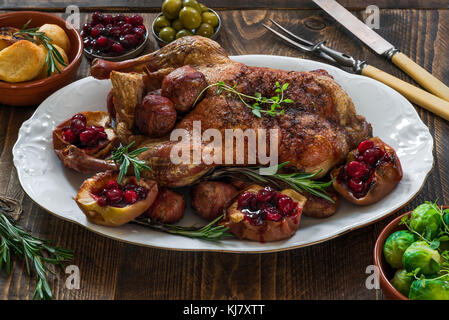 Canard rôti de fête avec les choux de Bruxelles, sauce aux canneberges et pommes de terre de table en bois - vue de l'angle d'un paraprofessionnel Banque D'Images