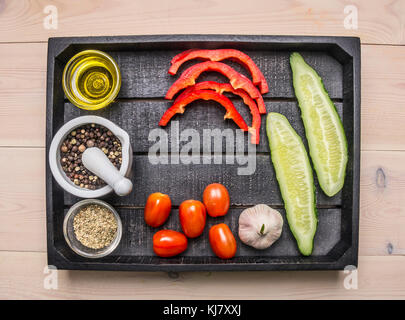 Ingrédients pour la cuisine végétarienne salade avec les herbes et le beurre disposés dans un plateau en bois concombres, poivrons, tomates cerises et l'ail Banque D'Images