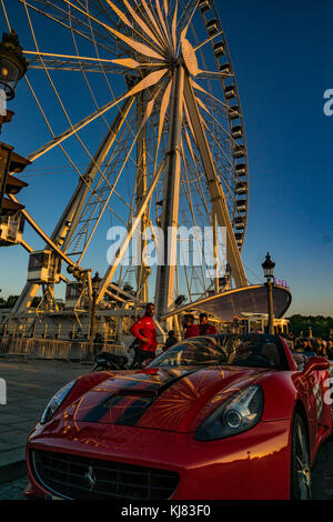 Paris, France. Une voiture de sport Ferrari à proximité d'une grande roue de la Place de la Concorde, près de l'obélisque de Louxor et Le Jardin des Tuileries. Banque D'Images