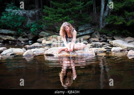 Young woman enjoying nature, calme paisible sur la rivière Red Creek dans la région de Dolly Sods, Virginie de l'Ouest au cours de journée ensoleillée avec réflexion trempant dans l'eau pour les mains Banque D'Images