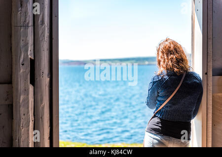 Vue arrière d'un seul, seul, jeune femme aux cheveux rouges l'article entrée par porte ouverte à la nature de l'océan Pacifique en vue, falaise, côte en ru Banque D'Images