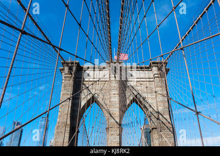 Une des tourelles en pierre du pont de Brooklyn et un drapeau américain sur le dessus Banque D'Images