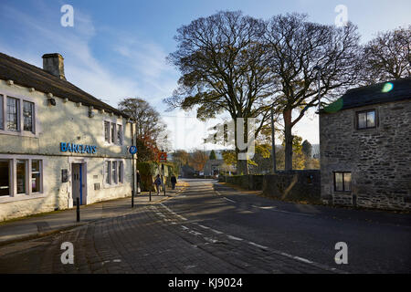 Fin d'après-midi Cours d'eau à travers les hêtres hivernal sur la jonction de la B6265 et l'extrémité inférieure de Grassington pavées de la rue principale. Barclays éclairage Banque D'Images