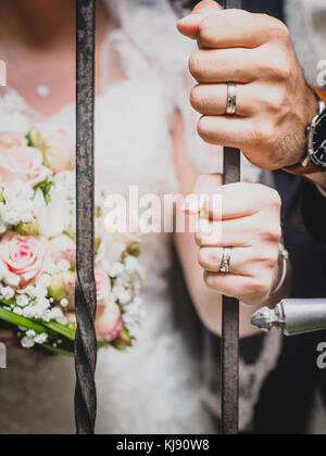 Un couple de jeunes mariés met la main sur une barre de fer montrant leur mariage. Banque D'Images