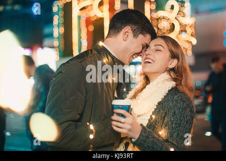 Jeune couple embrasser et s'étreindre dans la rue la nuit en plein air à l'époque de Noël Banque D'Images