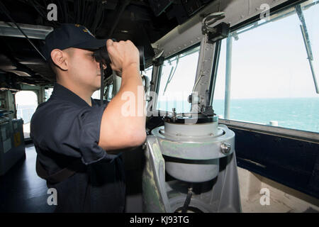 ZONE D'EXPLOITATION DE LA 5E FLOTTE DES ÉTATS-UNIS (NOV 12, 2017) Ens. Jose Vazquez, originaire de Brownsville, Texas, affecté au département technique à bord du navire amphibie USS Pearl Harbor (LSD 52), regarde à travers des jumelles tout en regardant debout sur le pont du navire pendant un passage en faux détroit. Pearl Harbor est déployé dans la zone d'opérations de la 5e flotte des États-Unis à l'appui des opérations de sécurité maritime visant à rassurer les alliés et les partenaires, et à préserver la liberté de navigation et la libre circulation du commerce dans la région. (É.-U. Photo de la marine par Mass communication SPE Banque D'Images