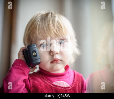 Petite fille dans une robe rouge à parler au téléphone Banque D'Images