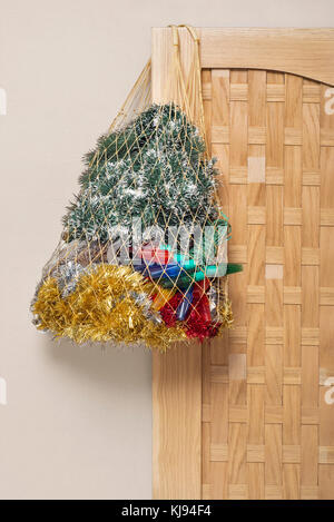 Sac-filet plein de guirlandes, de lumières pour arbre de Noël accroché sur la porte de bois Banque D'Images