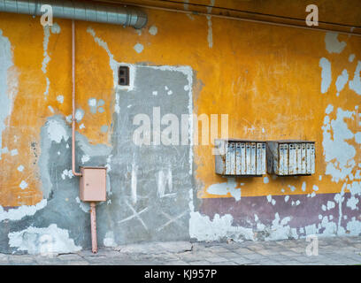 Boîtes rouillées sur mur en stuc jaune craquelé Banque D'Images