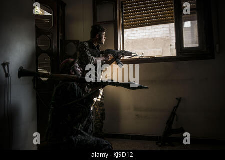 Raqqa, la Syrie. 12Th aug 2017. sdf vu les soldats qui gardaient la street à partir d'une fenêtre.en été 2017 les forces démocratiques syriennes (SDF) a lancé une bataille contre isis dans raqqa afin de reprendre le contrôle de la ville à partir de l'organisation terroriste. l'opération a donné lieu à au moins 3 000 morts y compris les combattants des deux côtés et civils. crédit : jake simkin/sopa/zuma/Alamy fil live news Banque D'Images