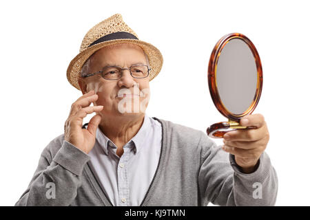 Un homme âgé en se regardant dans un miroir et de toucher son visage isolé sur fond blanc Banque D'Images