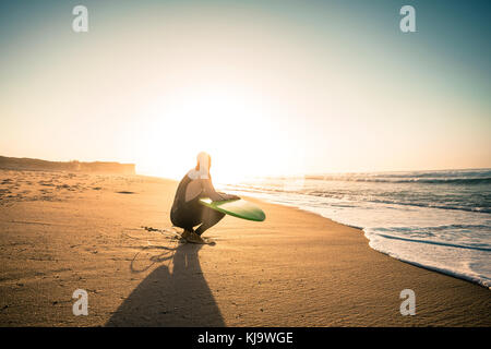 Surfeur sur la plage holding est surfboaerd et regarder les vagues Banque D'Images