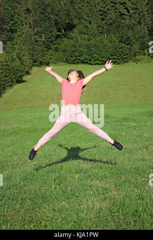 Happy little girl jumping on field Banque D'Images