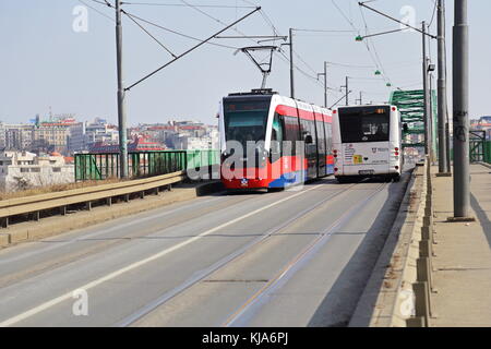 Nouveau Rouge CAF Urbos tram 3 et bus blanc sur l'ancien pont de la Save (tram Pont) à Belgrade, Serbie Banque D'Images