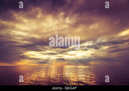 L'océan spectaculaire coucher de soleil avec des nuages de tempête de pluie et rayons de soleil Banque D'Images