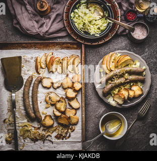 Sur la plaque de cuisson des saucisses frites servi sur assiette avec la salade de chou blanc et de la moutarde sur la table de cuisine rustique dip, vue d'en haut. La nourriture allemande concept. Banque D'Images