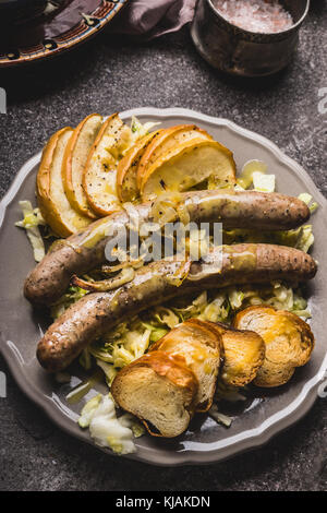 Servi avec des saucisses frites de pommes cuites, oignons et pain grillé servi sur lye table rustique avec salade de chou blanc, vue du dessus, à proximité de la nourriture allemande. Banque D'Images