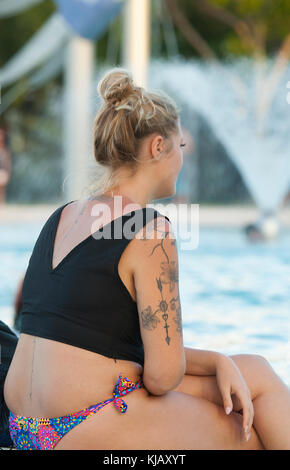 Jeune femme blonde portant des tatouages s'assit au bord de la lagune à l'extrême nord du Queensland, Cairns, Queensland, Australie, FNQ Banque D'Images