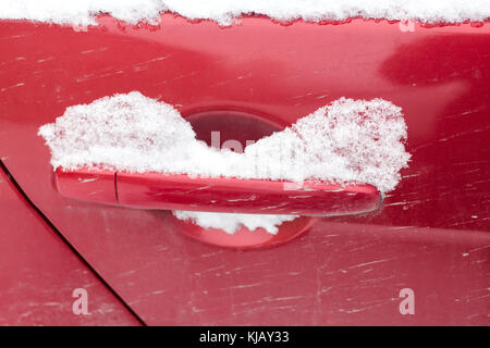 Poignée de porte de voiture rouge unique recouvert de neige fraîche. le verrou a été bloqué fermé. . Banque D'Images