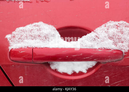 Poignée de porte de voiture rouge unique recouvert de neige fraîche. le verrou a été bloqué fermé. Banque D'Images