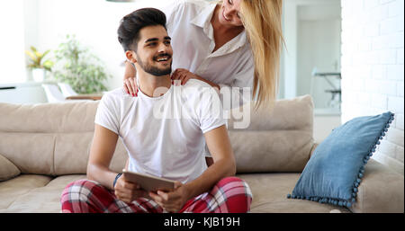 Cute couple relaxing on couch with tablet Banque D'Images