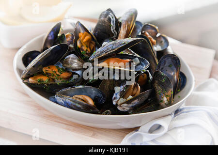 Moules cuites dans un bol blanc sur base de bois Banque D'Images