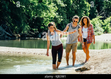 Smiling friends wading in river Banque D'Images