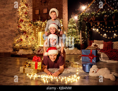 Famille dans une pièce avec un arbre de Noël à Noël. Banque D'Images