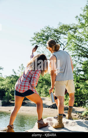 Friends posing for cell phone sur des rochers près de river selfies Banque D'Images