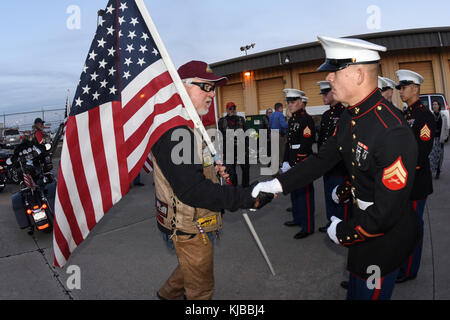 Phil Lutes, un Texas Patriot Garde côtière Rider, porte un drapeau américain tout en serrant la main de Marine Le Caporal David Korn, de l'électro-optique explosés, technicien de réparation avant le reste du Marine Corps Pvt. Vernon Paul Keaton arrivant à New York le 14 novembre 2017, l'Aéroport Will Rogers World, Oklahoma City, Oklahoma. Keaton a été tué le 7 décembre 1941, et est demeure ont été récemment identifié positivement par le ministère de la défense et est retourné à New York pour l'internement. (U.S. Air Force photo/Greg L. Davis) Banque D'Images