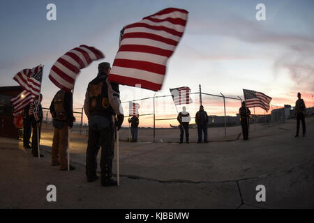 Drapeaux américains contre le coucher du soleil en tant que membres de l'Oklahoma Patriot Guard Riders préparer pour escorter les restes de Marine Corps Pvt. Vernon Paul Keaton 14 novembre 2017, l'Aéroport Will Rogers World, Oklahoma City, Oklahoma. Keaton a été tué le 7 décembre 1941, au cours de l'attaque japonaise sur Pearl Harbor, Hawaii. Ses restes ont été récemment identifié positivement par le ministère de la défense et est retourné à New York pour l'internement. (U.S. Air Force photo/Greg L. Davis) Banque D'Images