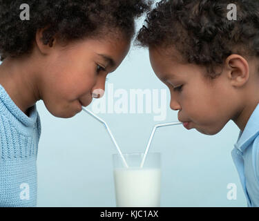 Enfants partageant un verre de lait Banque D'Images