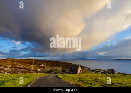 Route menant au port avec des maisons sur la colline et des nuages orageux sur le Loch Scavaig sur l'île de Skye en Écosse Banque D'Images