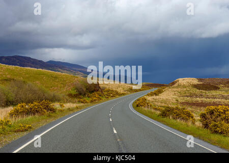 Route sinueuse avec raintouds au printemps sur l'île de Skye en Écosse, au Royaume-Uni Banque D'Images