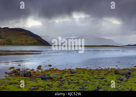 Rainclouds sur les rives herbeuses le long de la côte écossaise près du château Eilean Donan et de Kyle de Lochalsh en Écosse Banque D'Images