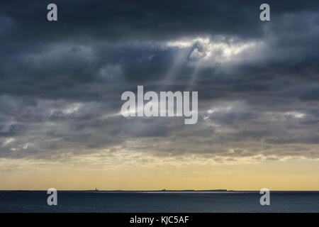 Soleil qui brille à travers les nuages de pluie au-dessus de l'île Farne dans la mer du Nord à Bamburgh, Angleterre, Northumberland Banque D'Images