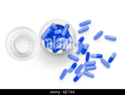Couleur bleu heap de pilules contre le tube de remplissage de fond blanc. vue d'en haut. Une mise au point nette sur le dessus du pot et soft focus sur le contexte . Banque D'Images