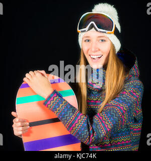 Souriante jeune fille en vêtements de ski snowboard avec sur fond noir en studio. Banque D'Images