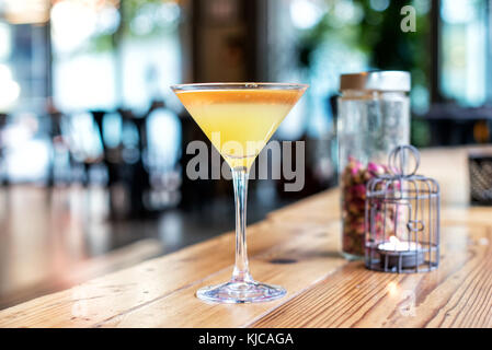 Close-up of a cocktail sans alcool jaune doux dans un verre a pied sur un comptoir en bois à l'intérieur d'un bar Banque D'Images