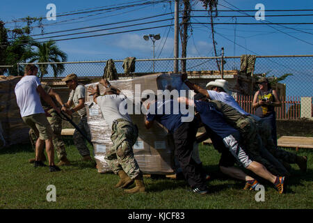 LOS LLANOS, Porto Rico - Les soldats de l'armée américaine avec le 402ème bataillon d'affaires civiles, affaires civiles, 350e commandement de l'armée des États-Unis, Samaritan's Purse, volontaires et bénévoles locaux travaillent ensemble pour décharger l'épicerie pour distribution dans le cadre d'une église locale, le 14 novembre 2017. Les différents groupes ont travaillé ensemble pour distribuer la nourriture pour 1 000 familles dans la région. (U.S. Photo de l'armée par le Sgt. Avery Cunningham) Banque D'Images