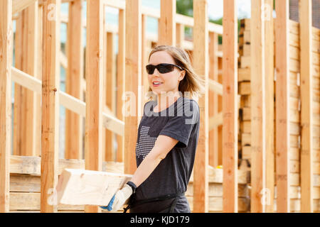 Caucasian woman carrying lumber at construction site Banque D'Images