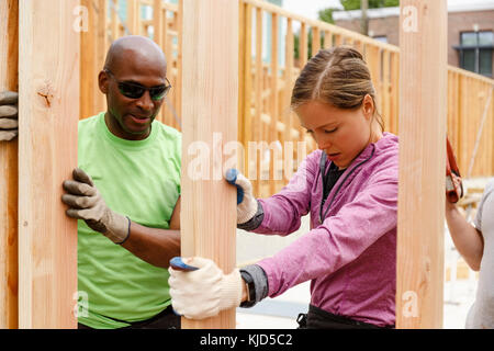 Les bénévoles holding wall at construction site Banque D'Images