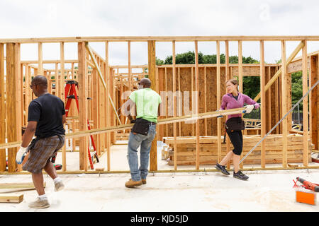 Les bénévoles carrying lumber at construction site Banque D'Images