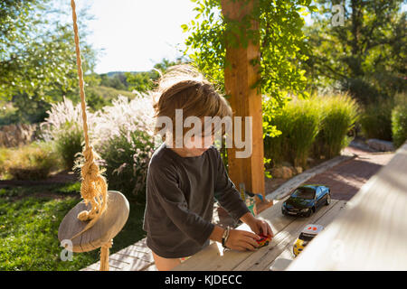 Caucasian boy playing with toy cars on patio Banque D'Images