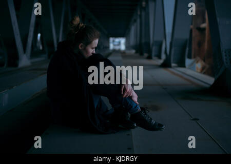 Caucasian woman sitting under bridge Banque D'Images