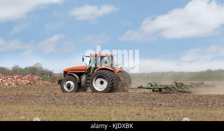Tractorpulling rouge une charrue labourant la terre Banque D'Images