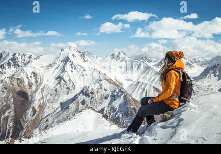 Une fille est assise sur le sommet de la montagne et profiter de la vue sur les pics de neige environs. Banque D'Images