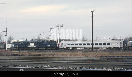 Cette photographie capture la locomotive Penn Central 4907 (GG1) aux côtés de la voiture d'essai à grande vitesse DOT au terminal Ivy City à Washington, DC, le 14 janvier 1969. L'image marque un moment important dans l'histoire du transport ferroviaire, mettant en valeur les avancées technologiques dans le domaine des trains à grande vitesse. Banque D'Images