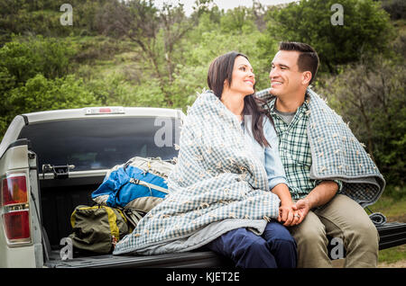 Couple assis sur une couverture de lit de camion Banque D'Images