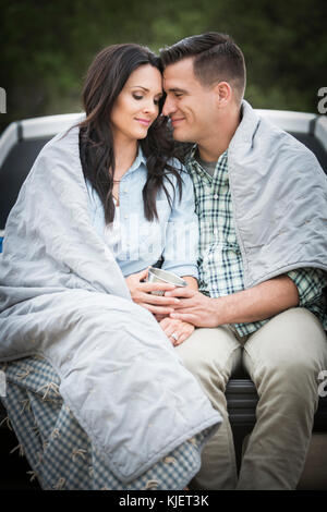 Couple assis sur une couverture de lit de camion Banque D'Images